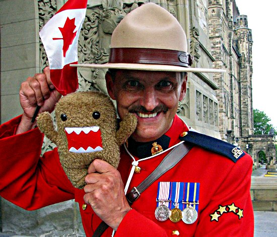 A Canadian mountie holding a domokun and a flag